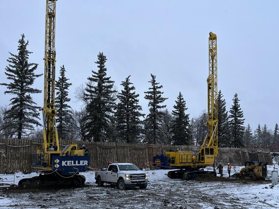 two construction rigs drilling shafts on snowy construction site